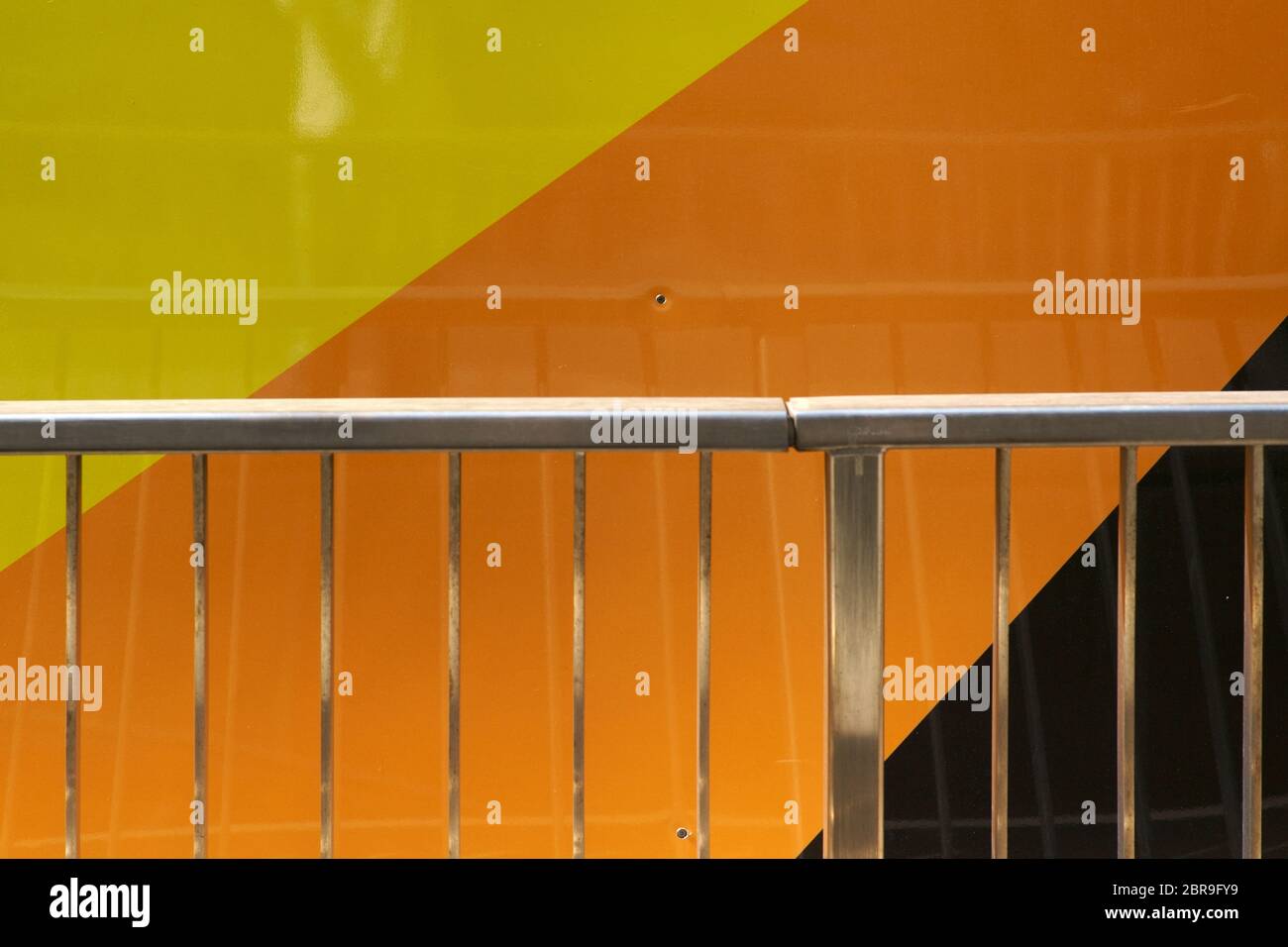 The closeup of a shiny steel handle in front of a colorful and modern metal facade. Stock Photo