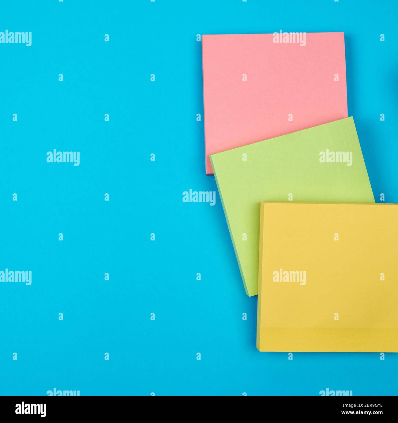 multicolored empty paper square stickers on blue background, copy space Stock Photo