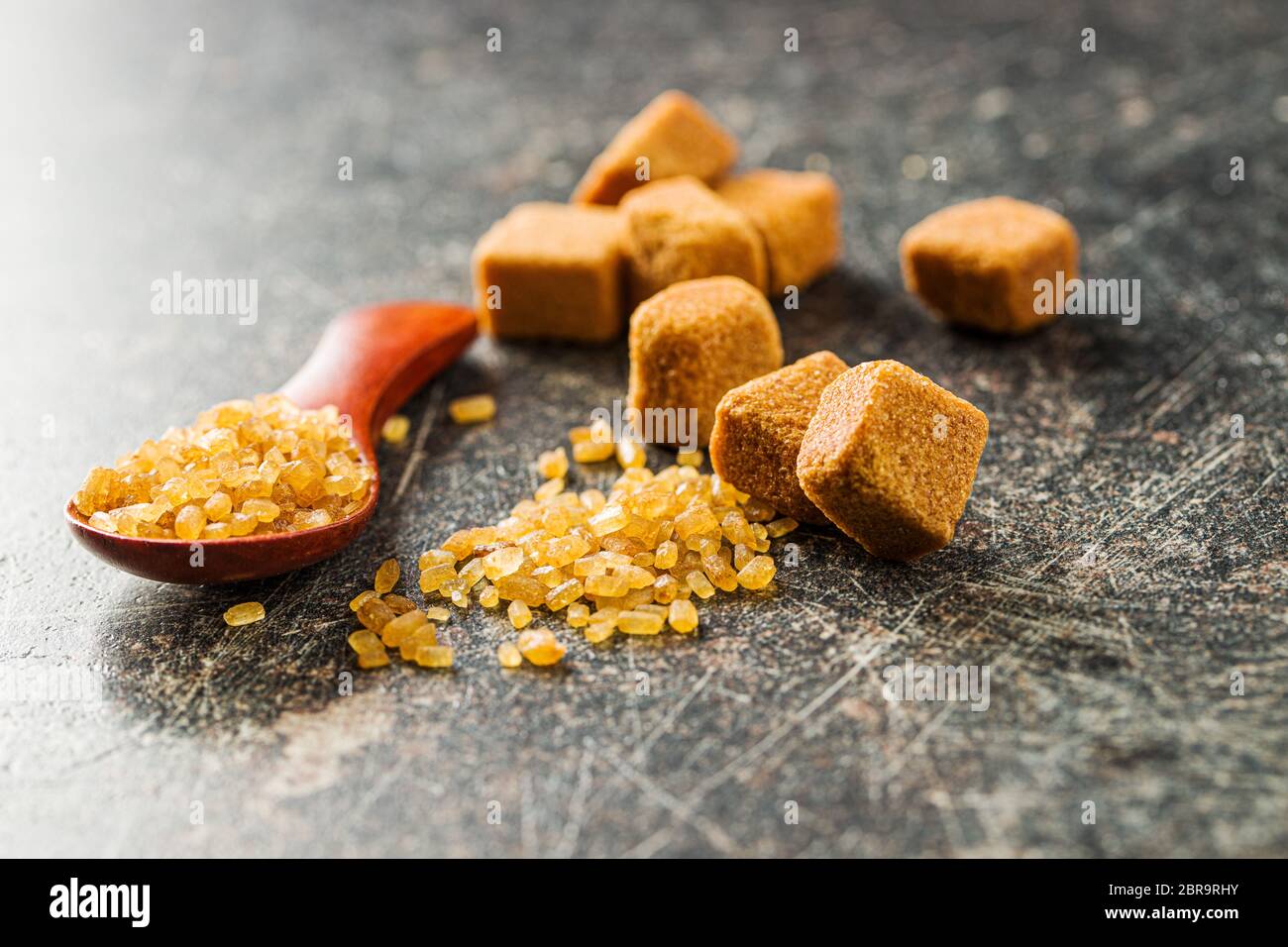 Crystalized brown sugar and sugar cubes on old kitchen table. Stock Photo