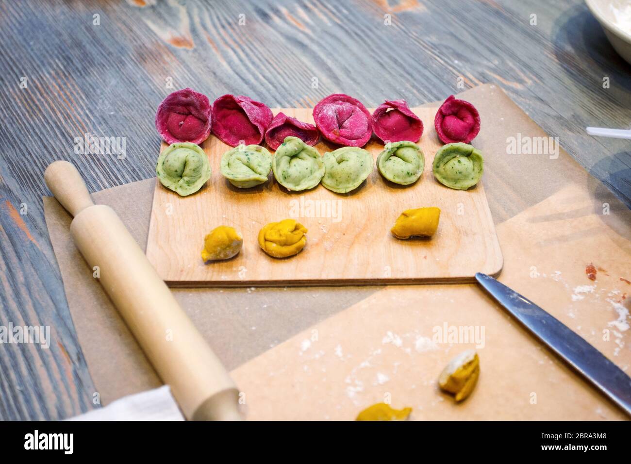 Cooking class, culinary. food and people concept, molding of colorful pelmeni or meat dumplings, national traditional food, creative color menu Stock Photo