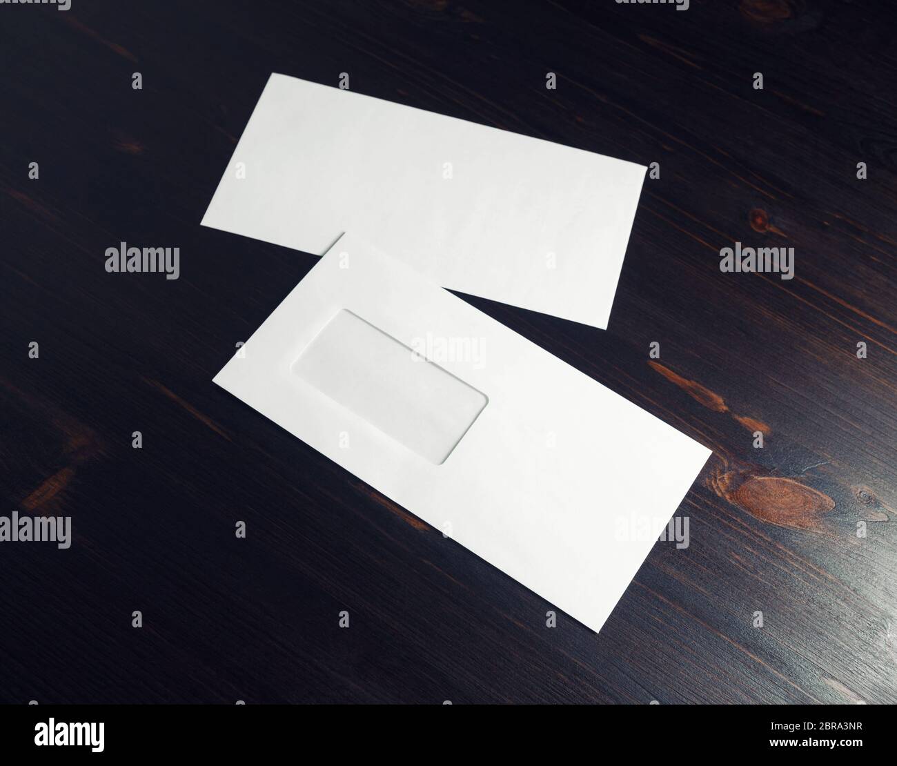 Two blank paper envelopes with window on dark wood table background