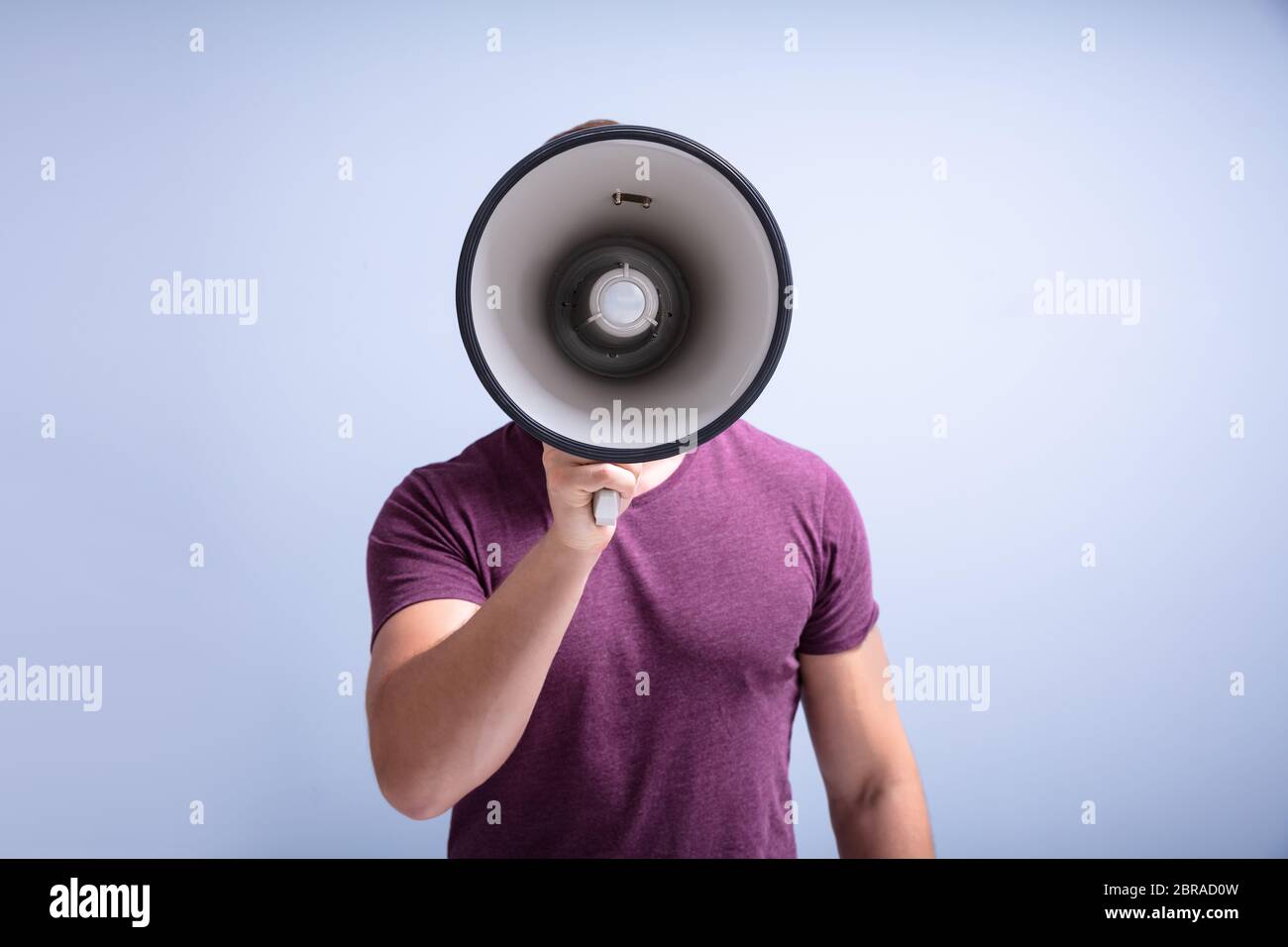 Close-up Of A Beard Man Shouting Through A Megaphone Against Gray Background Stock Photo