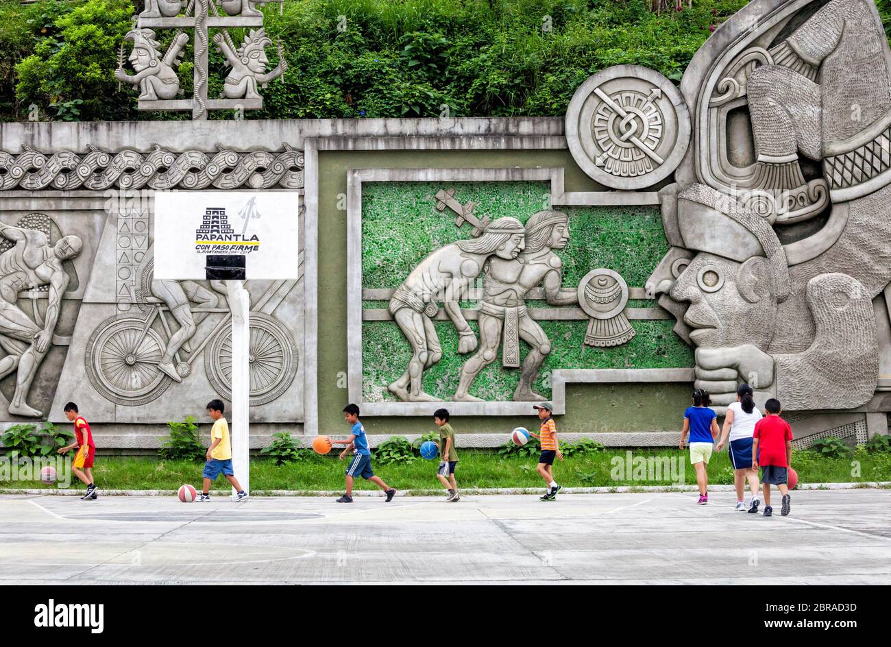 Children practice basketball surrounded by reminders of their heritage in Papantla, Veracruz, Mexico. Stock Photo