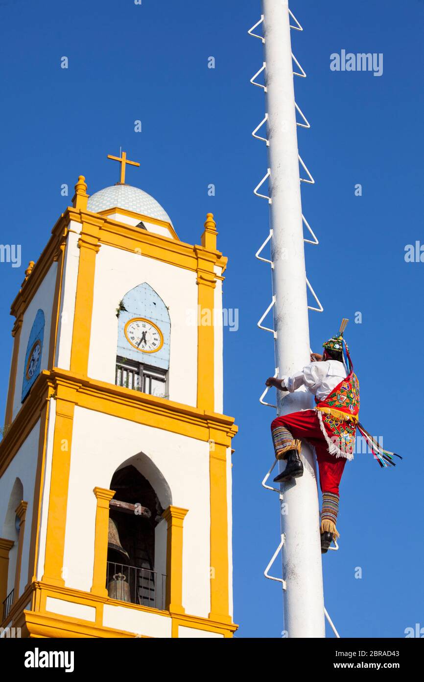 A volador (flyer) climbs the pole near the church temple in Papantla, Veracruz, Mexico. Stock Photo