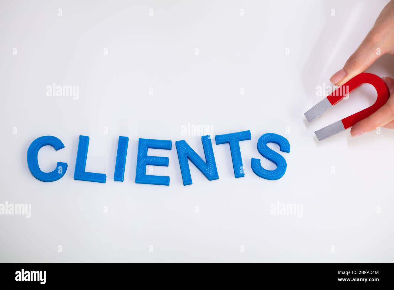 Businessperson Attracting Blue Clients Text With Horseshoe Magnet Over White Background Stock Photo