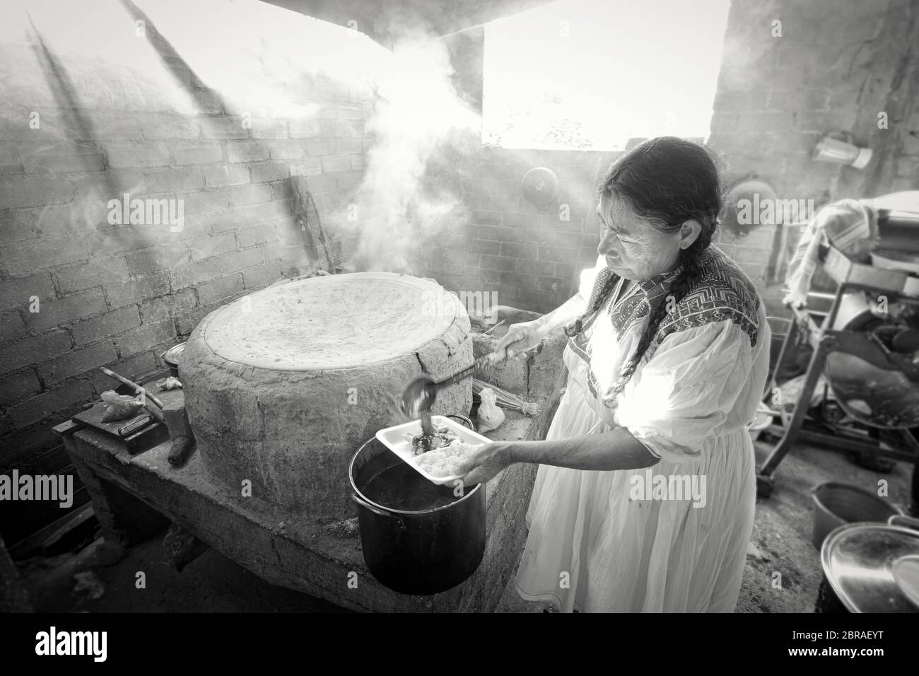 An indigenous cook serves up traditional mole sauce in a smoky hut in San Vicente Coatlan, Oaxaca, Mexico. Stock Photo