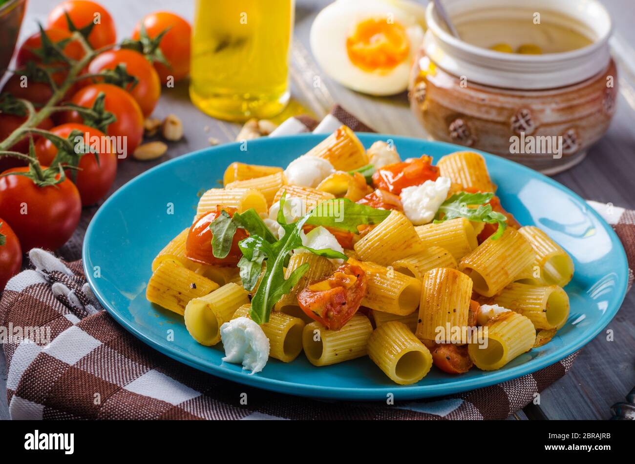 Rigatoni pasta with mozzarella and tomato, fresh herbs on top, very