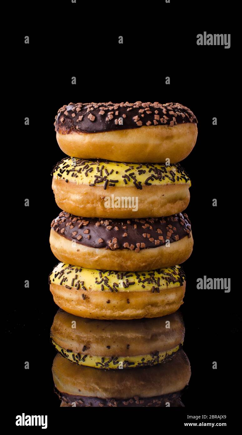 Donuts on reflection table, dark picture, chocolate and banana donuts Stock Photo