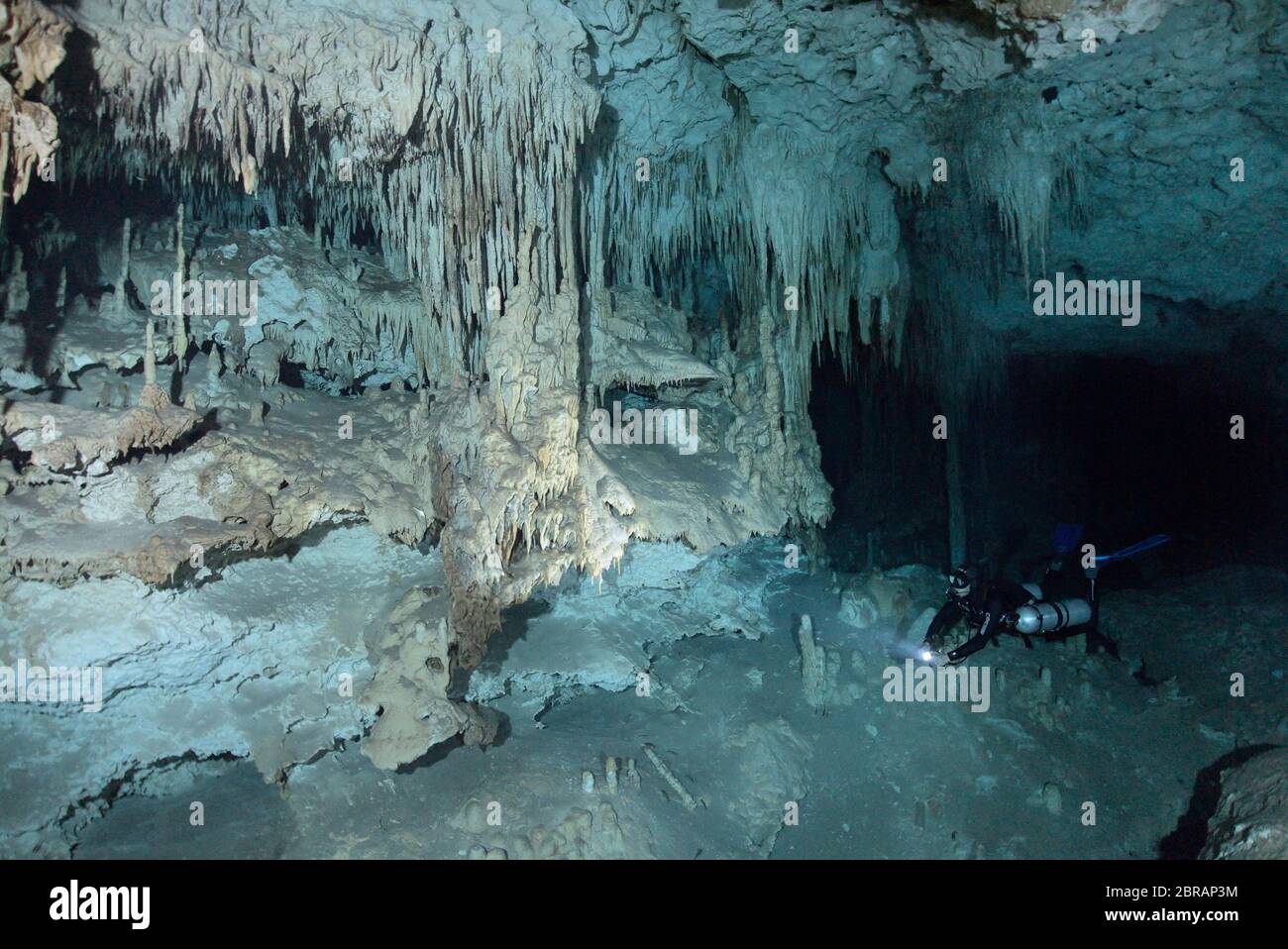 Sidemount technical diver swimming around unique limestone formations in the cenote Dreamgate in Mexico. Stock Photo