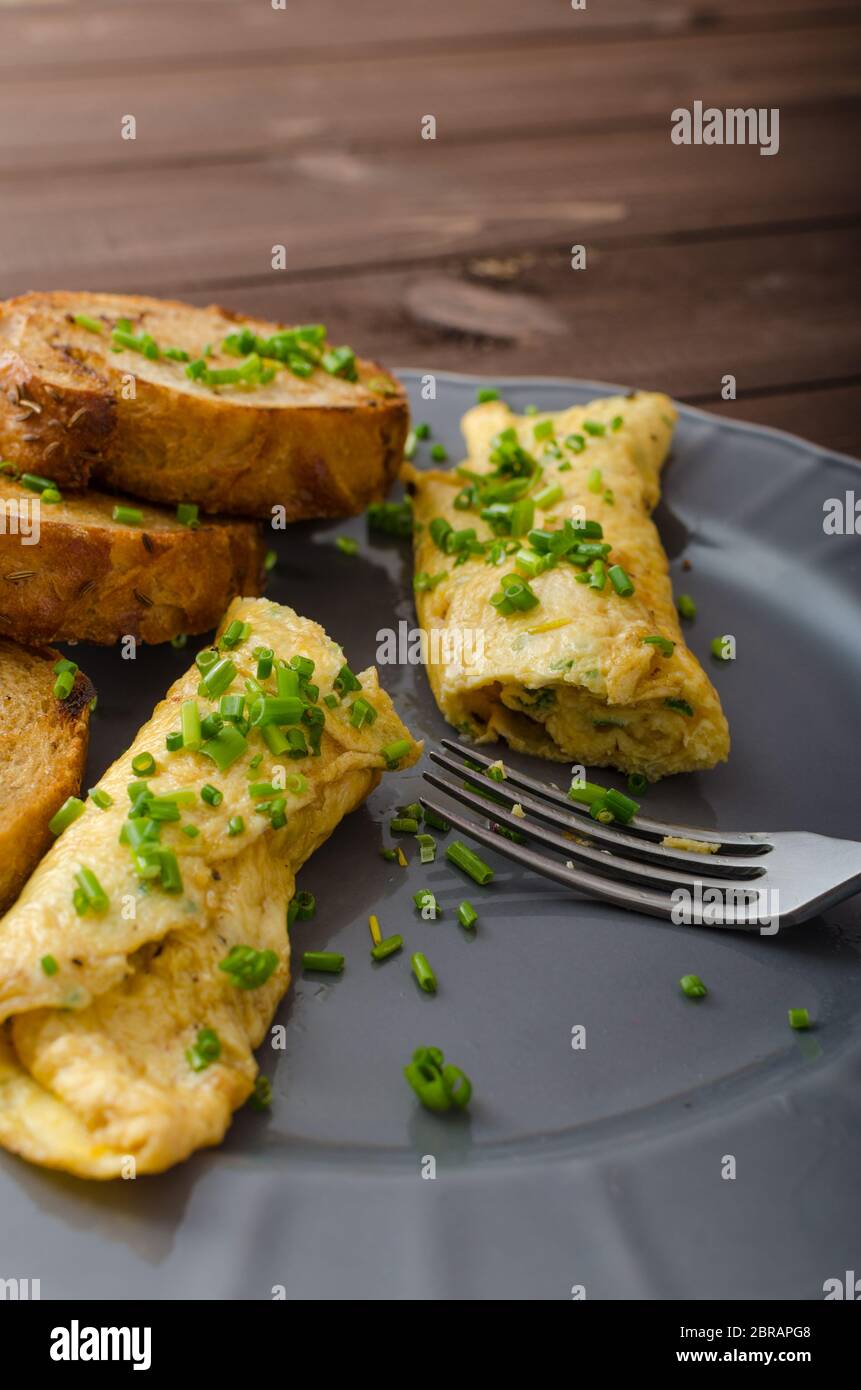 French omelette with chives, fresh herbs and garlic toast Stock Photo
