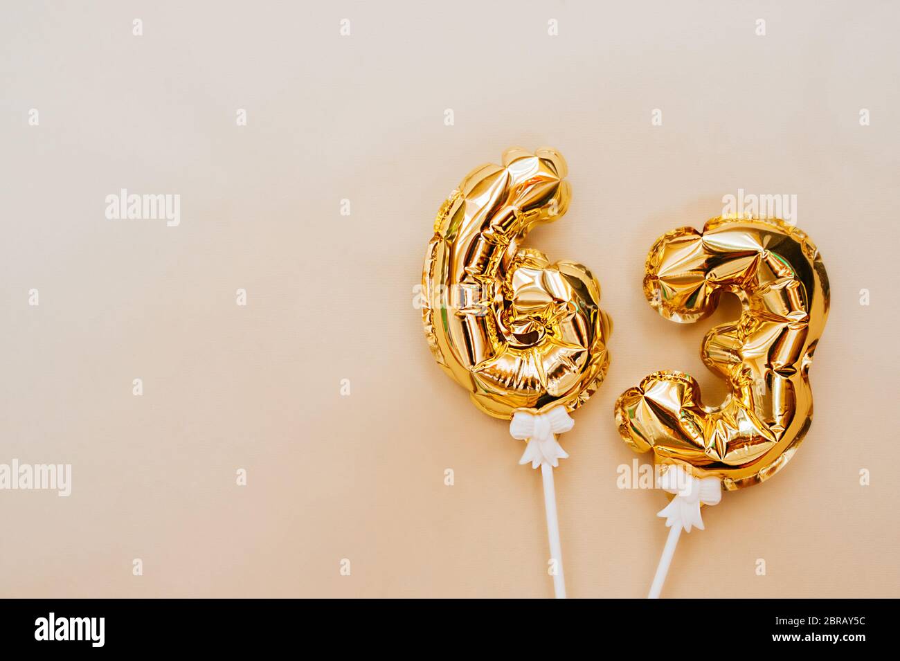 small foil gold balloons numbers 63 inflated with helium on a white stick  on a beige delicate background. glittering holiday greeting layout Stock  Photo - Alamy