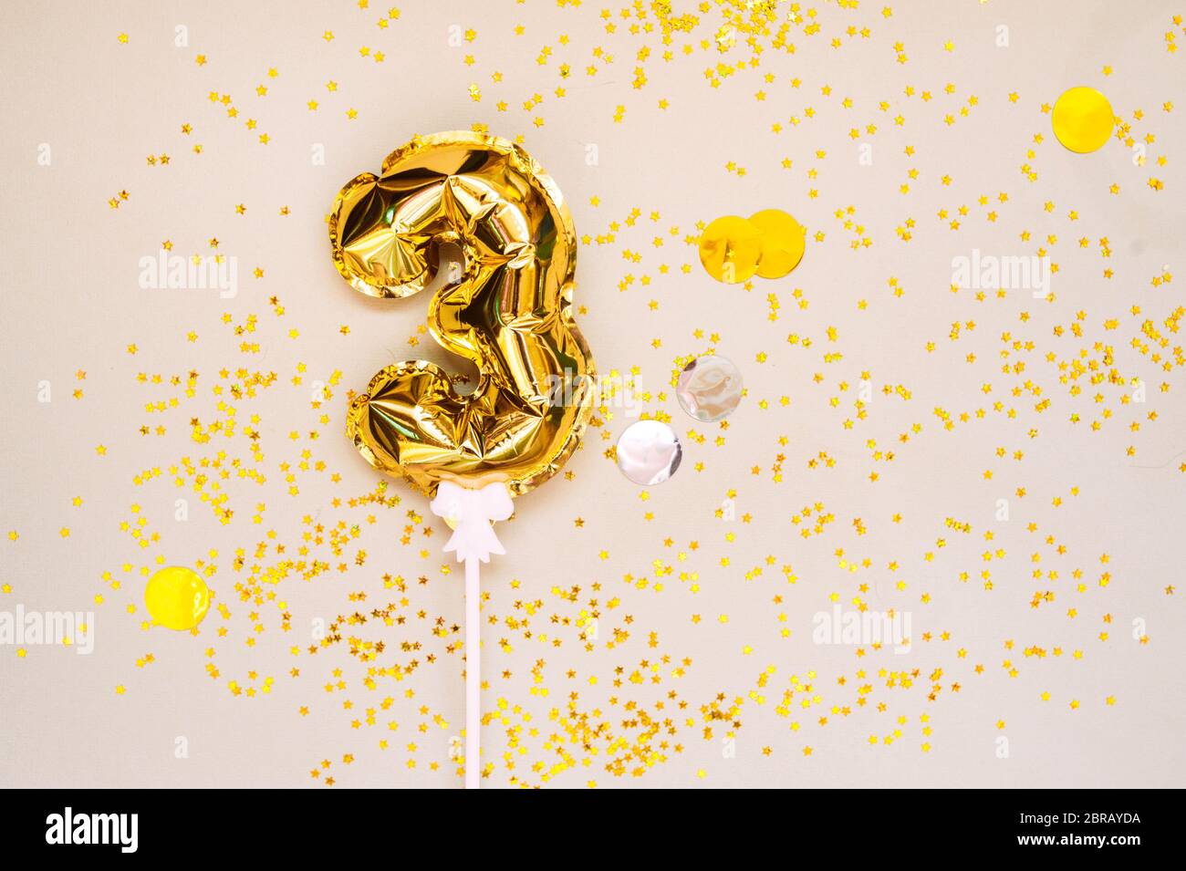small foil gold balloons numbers 3 inflated with helium on a white stick on  a beige delicate background with gold sequins stars and balls. glittering  Stock Photo - Alamy