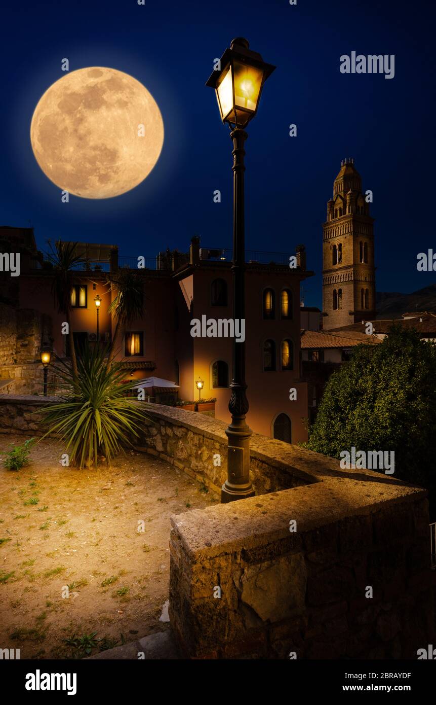 Gaeta Italy. The historic center of the city with a look to the Bell Tower of the Cathedral of Santa Maria, with street lights and a large full moon. Stock Photo