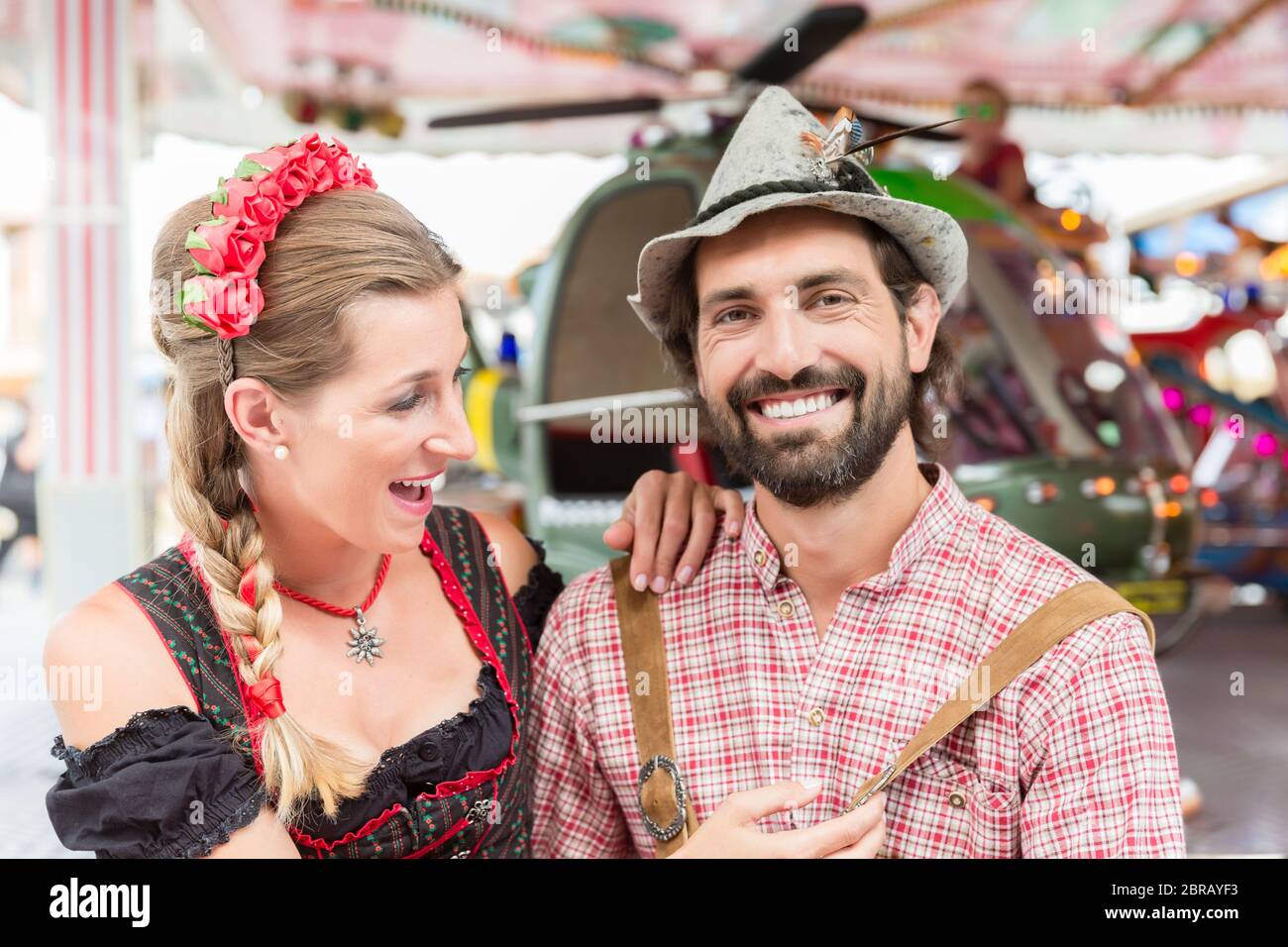 Couple in Tracht visiting carrousel at the Oktoberfest in Bavaria Stock Photo