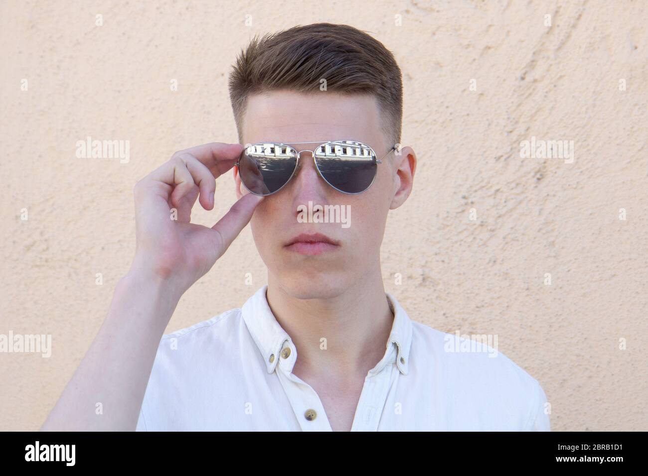 portrait of a handsome man dressed in white shirt against yellow wall ...