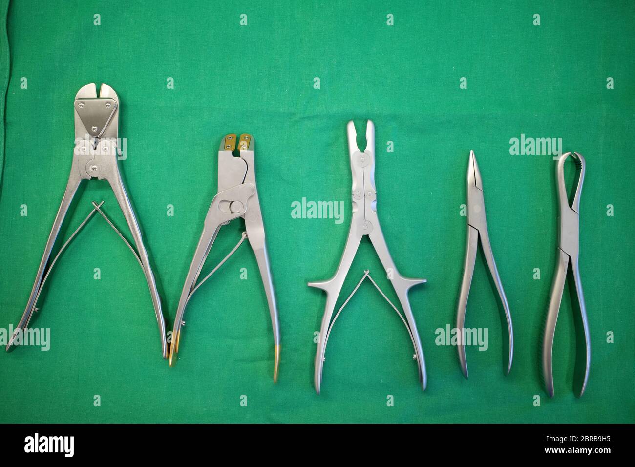 different surgical pliers lie side by side on a surgical drape Stock