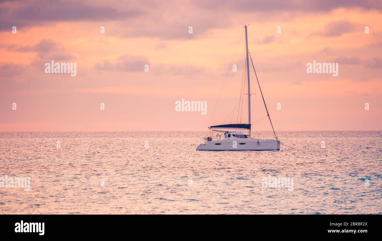 https://c8.alamy.com/comp/2BRBF2X/sunset-views-at-the-sea-with-a-yacht-or-silhouette-of-catamaran-luxury-travel-and-tourism-vacation-summer-recreational-background-seascape-2BRBF2X.jpg