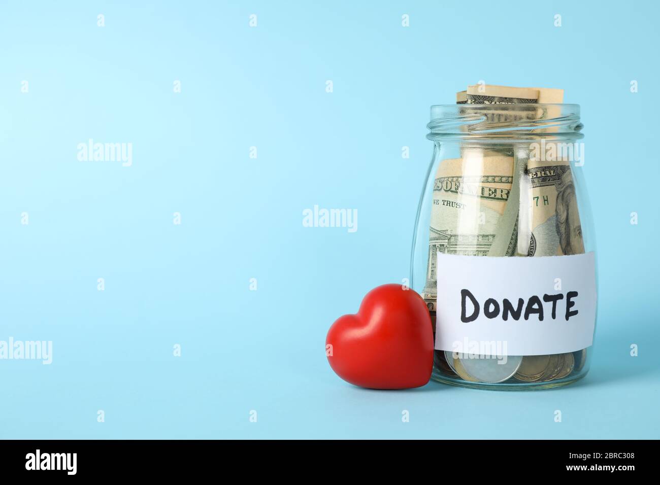 Glass jar with text Donate and heart on blue background Stock Photo Alamy