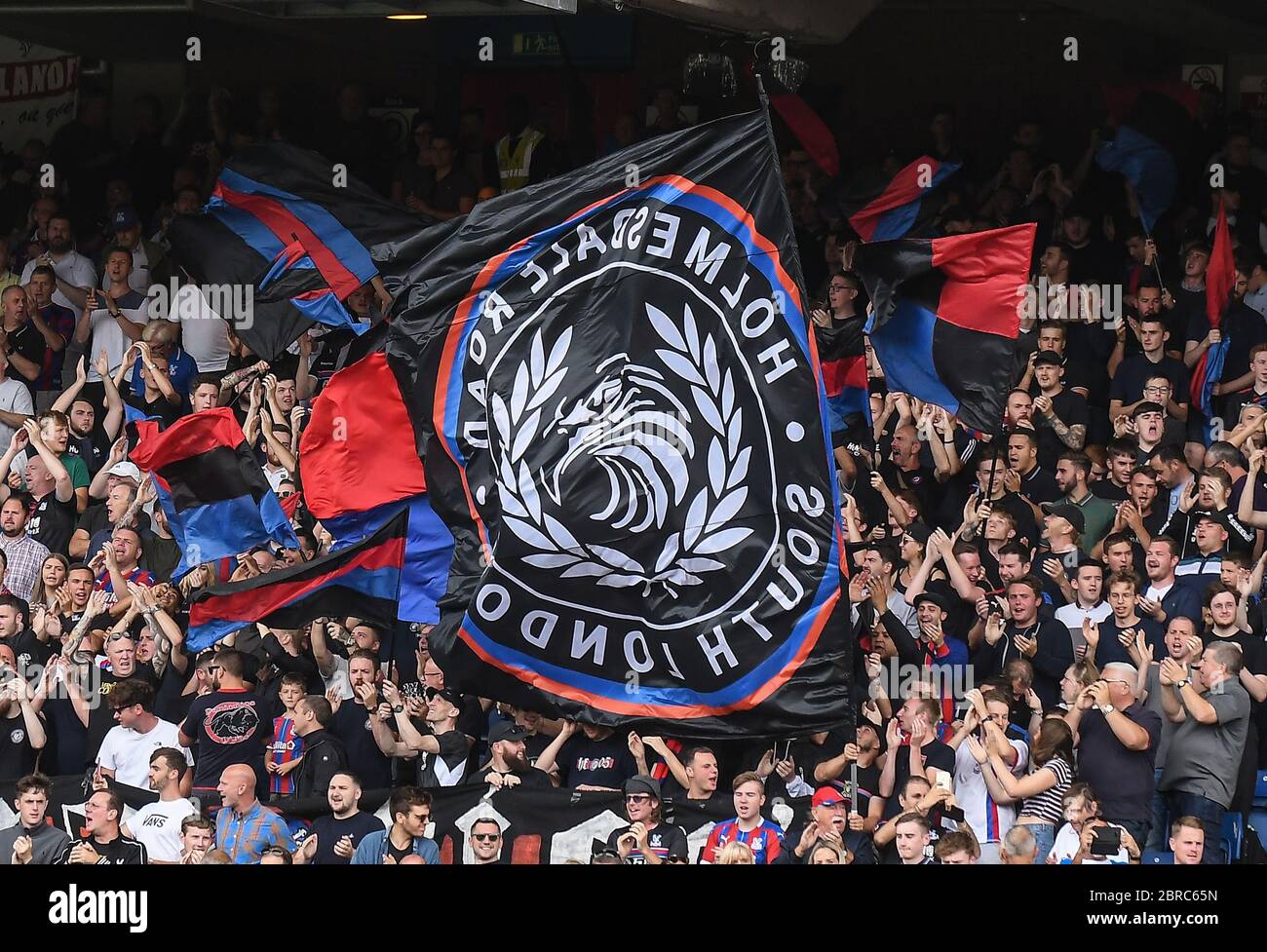 LONDON, ENGLAND - AUGUST 31, 2019: Palace ultras wave flags ahead of  the 2019/20 Premier League game between Crystal Palace FC and Aston Villa FC at Selhurst Park. Stock Photo