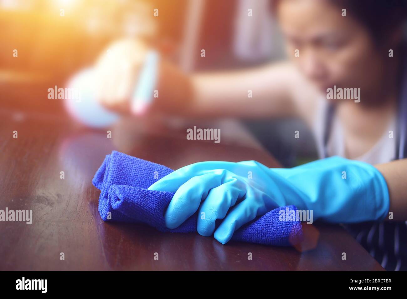 hand in blue rubber glove holding blue microfiber cleaning cloth and spray bottle with sterilizing solution make cleaning and disinfection Stock Photo