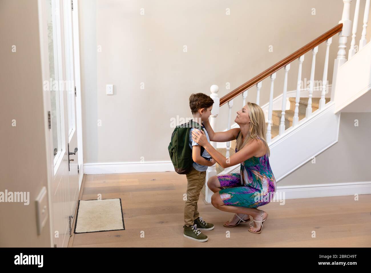 Caucasian woman kneeling with her son in the hallway Stock Photo