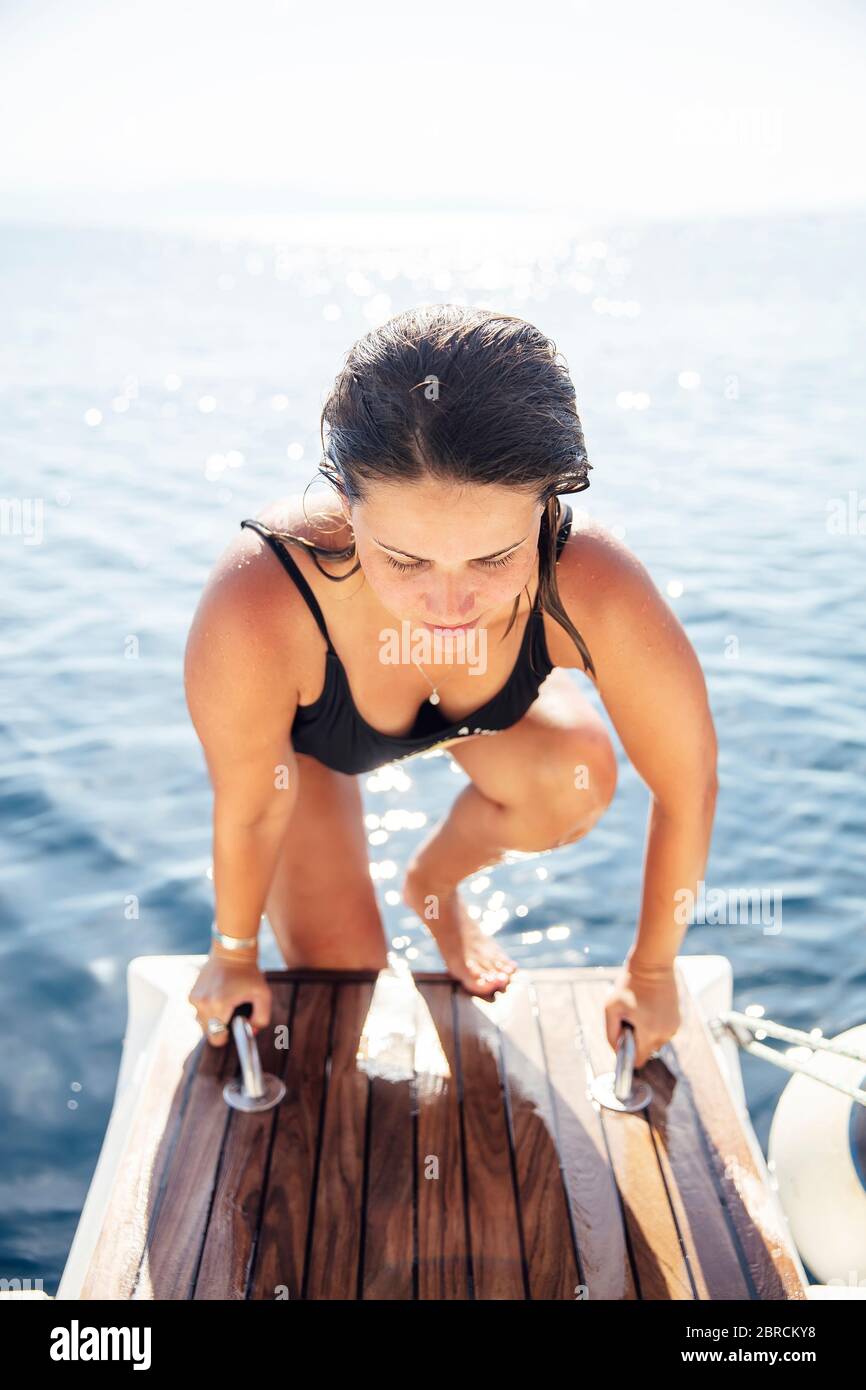 Pretty young woman get on the yacht on sea at sunny day Stock Photo