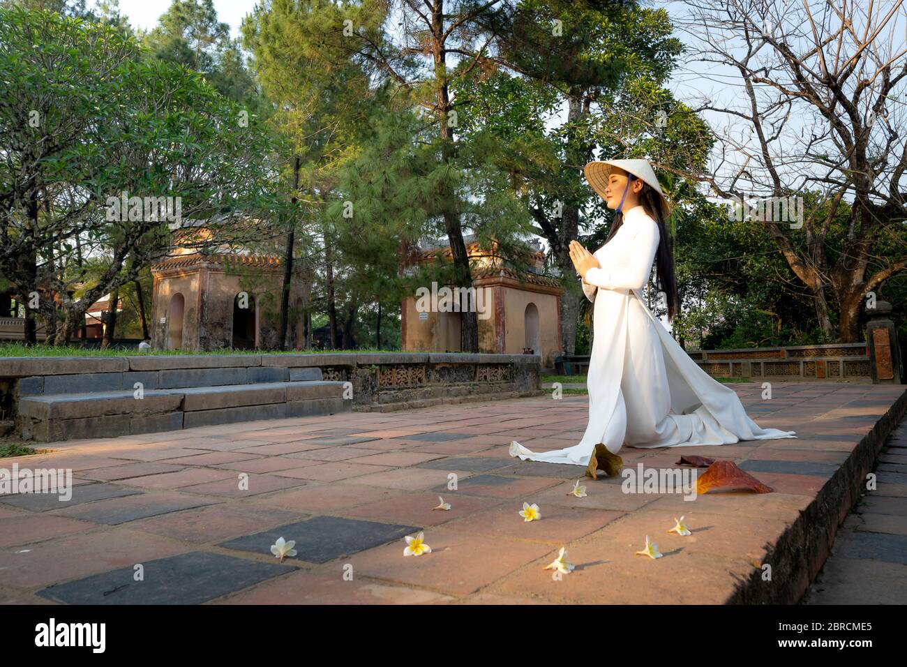 Hue City, Thua Thien Hue Province, Vietnam - May 7, 2020: A scene of a girl in a traditional ao dai costume praying inside a temple Stock Photo