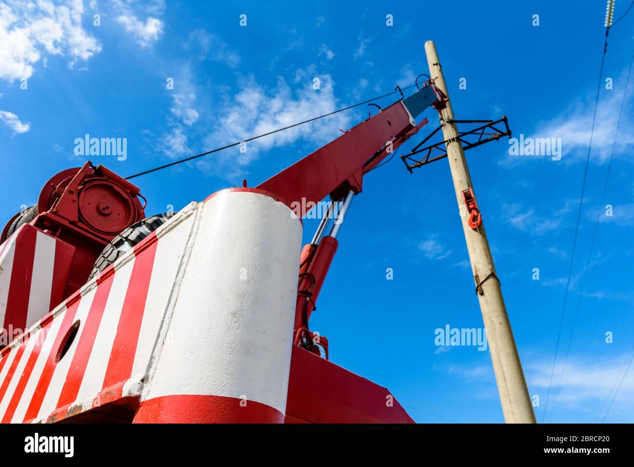Installation of column for high-voltage electricity line against the background of blue sky on a sunny summer day Stock Photo