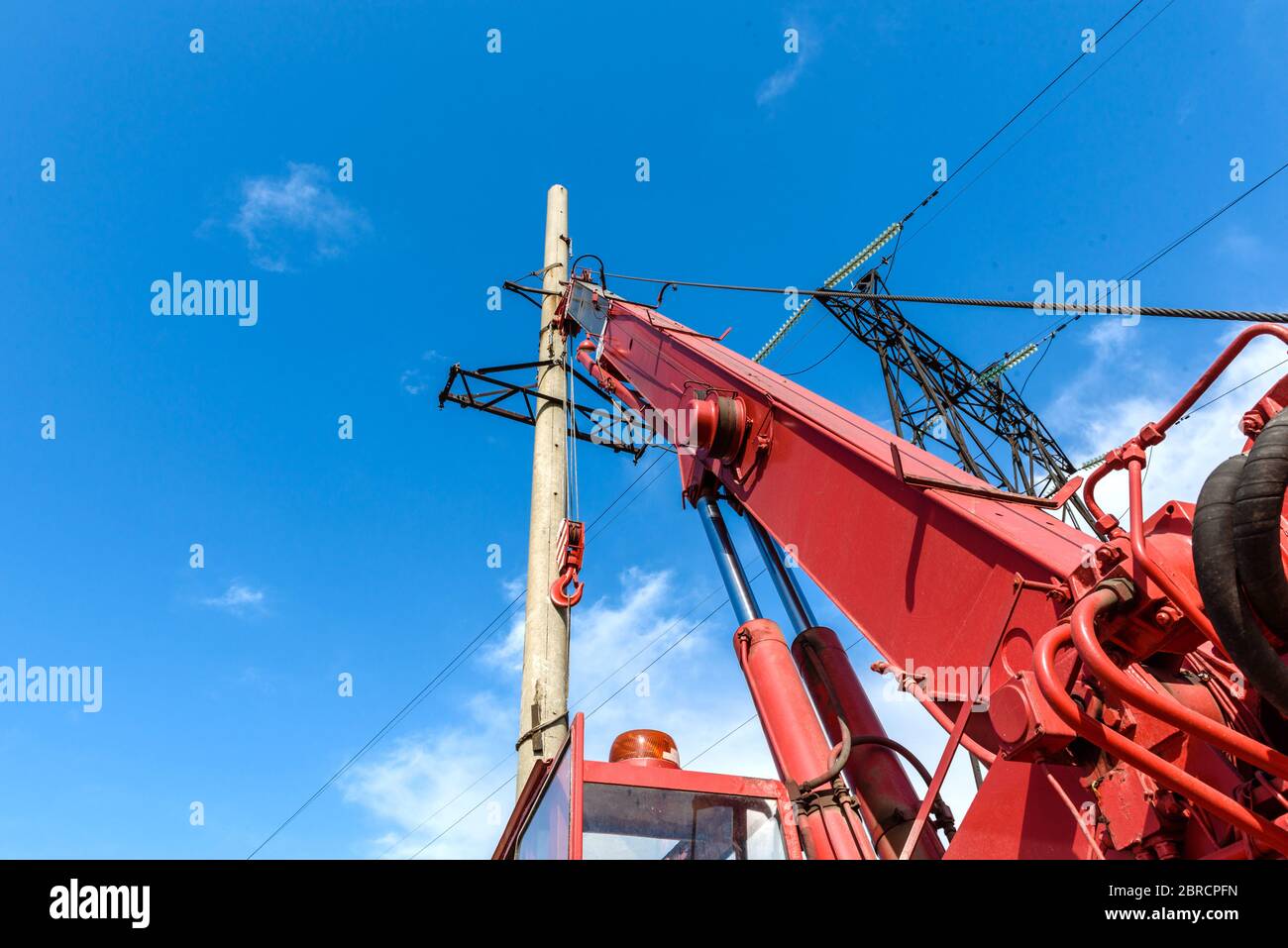 Installation of column for high-voltage electricity line against the background of blue sky on a sunny summer day Stock Photo