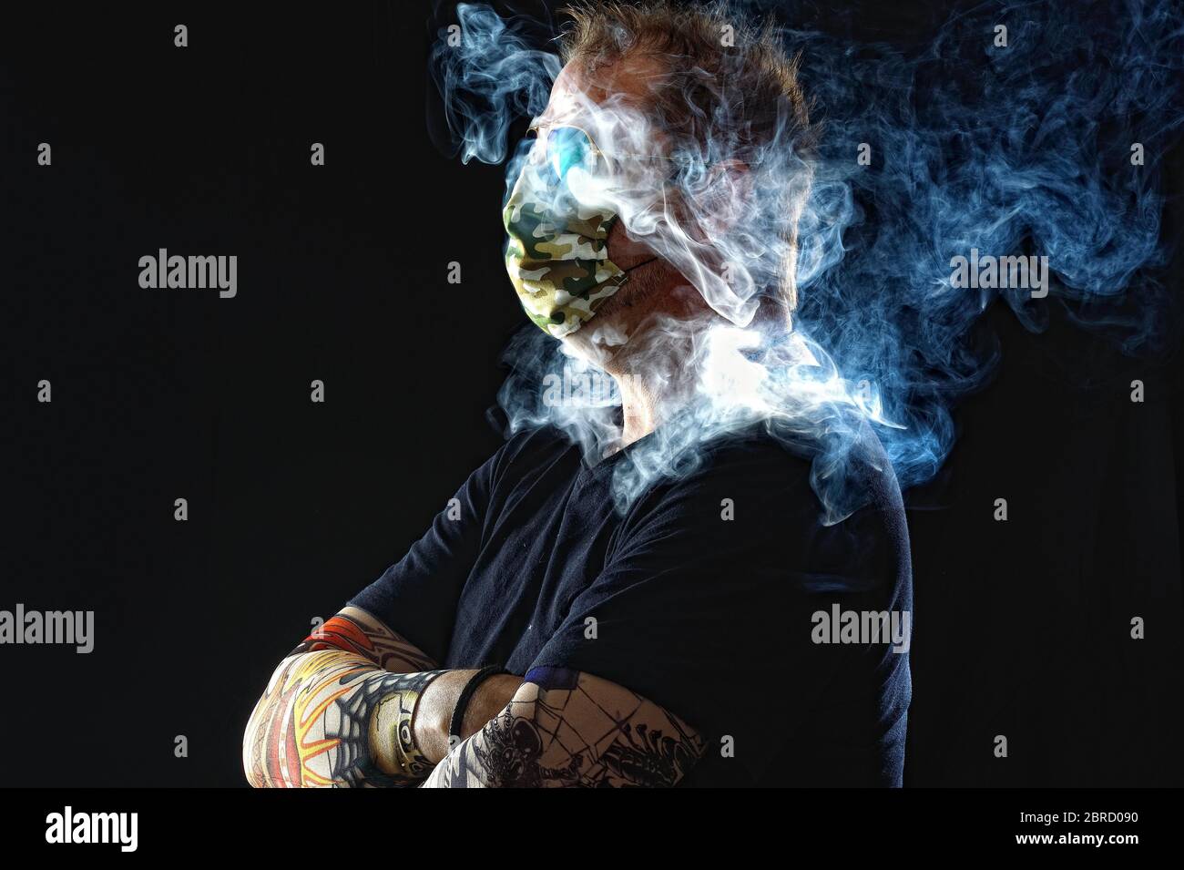 Man with face mask smoking cigarette, Corona series, Germany Stock