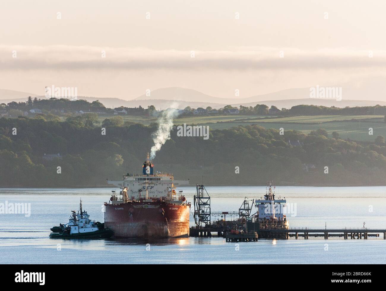 Whitegate, Cork, Ireland. 21st May, 2020. Oil tanker NS Champion is assisted by tug boats DSG Titan and Alex as she prepares to cast off at dawn after discharging her cargo of crude at the Irving Oil Refinery at Whitegate, Co. Cork, Ireland. Since the outbreak of the Covid-19 pandemic demand for oil has slumped on international markets which has resulted in a shortage of storage capacity worlwide. - Credit; David Creedon / Alamy Live News Stock Photo