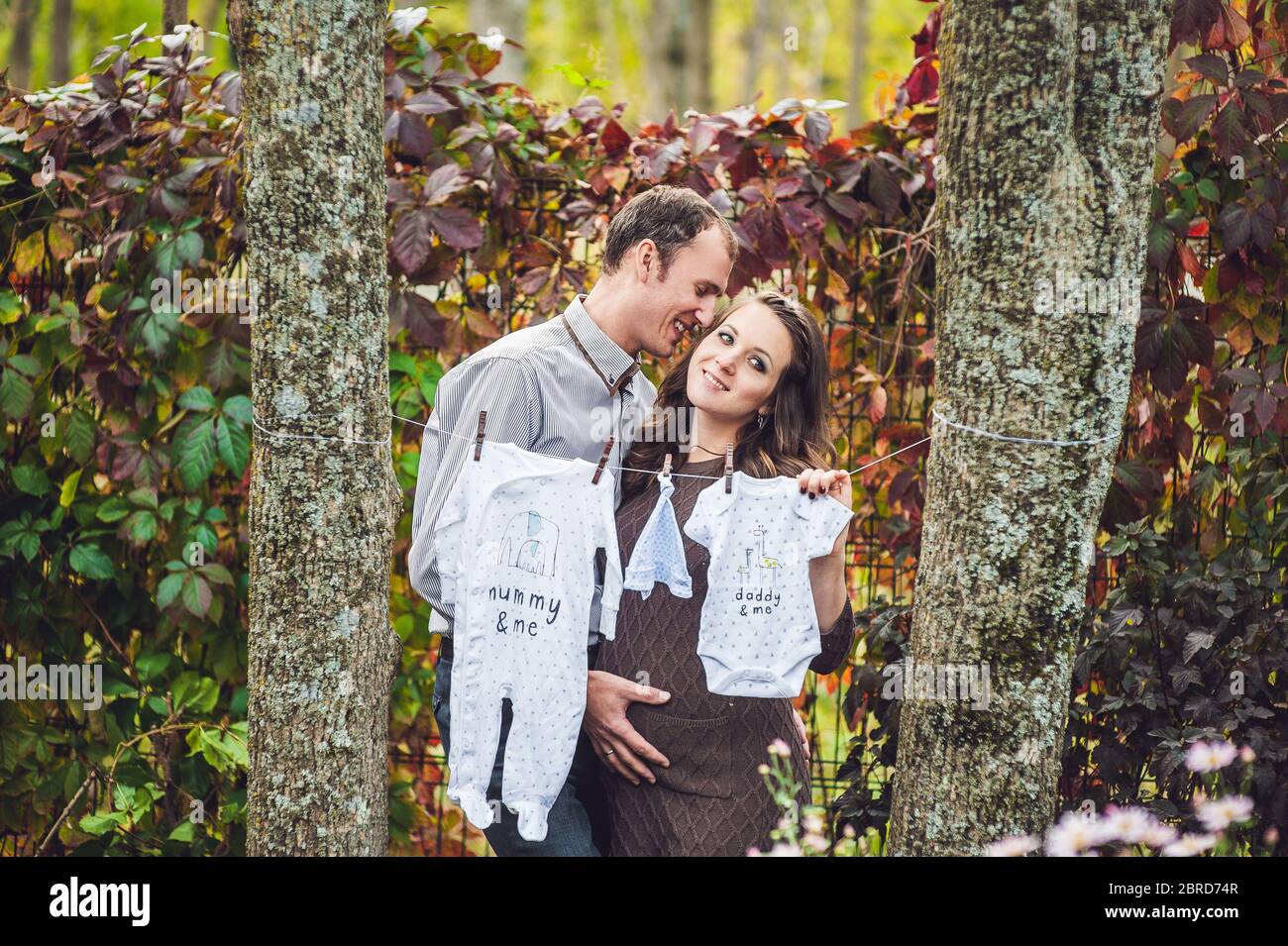 A pregnant young woman and her husband. A happy family hanging baby