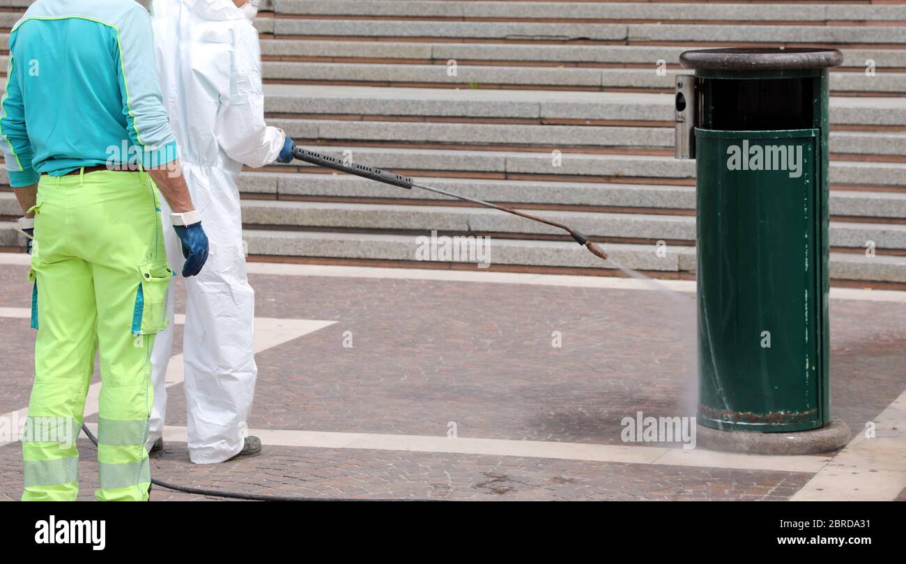 operating staff with protections during the disinfestation of city waste baskets Stock Photo