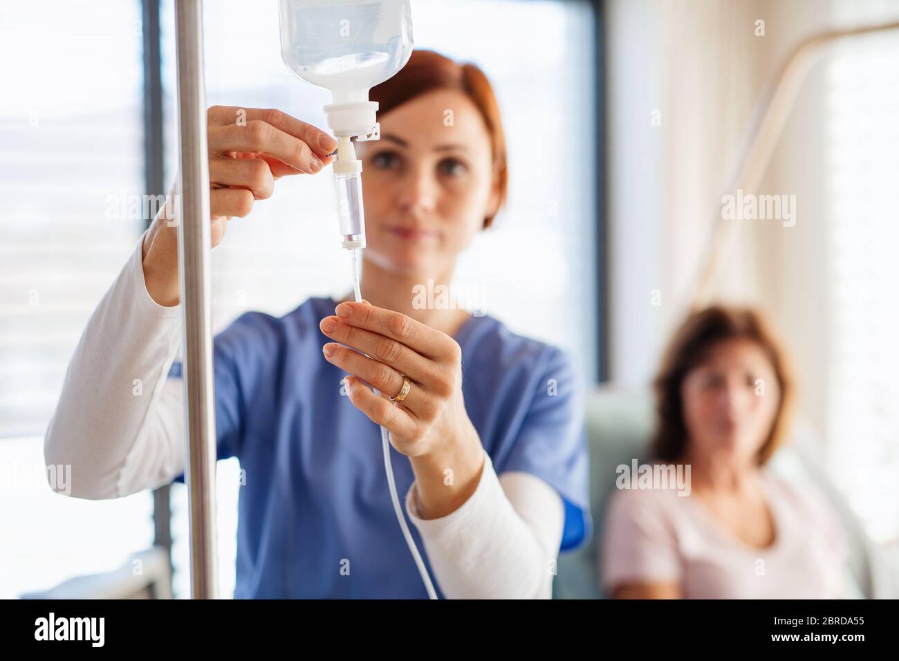 A nurse with IV drip and patient in bed in hospital room Stock Photo ...