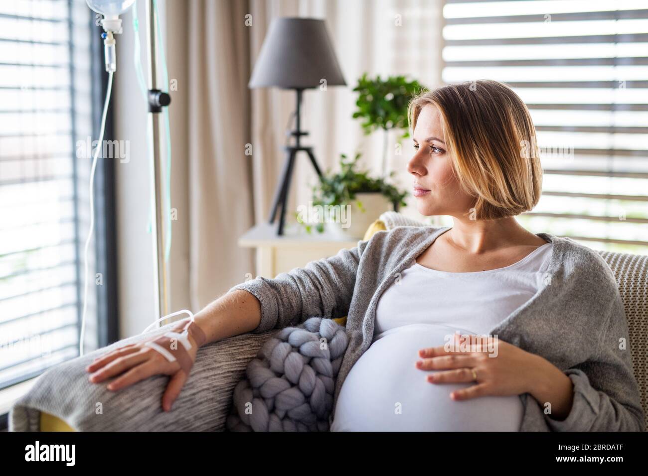 A portrait of pregnant woman with IV drip indoors at home or in hospital. Stock Photo