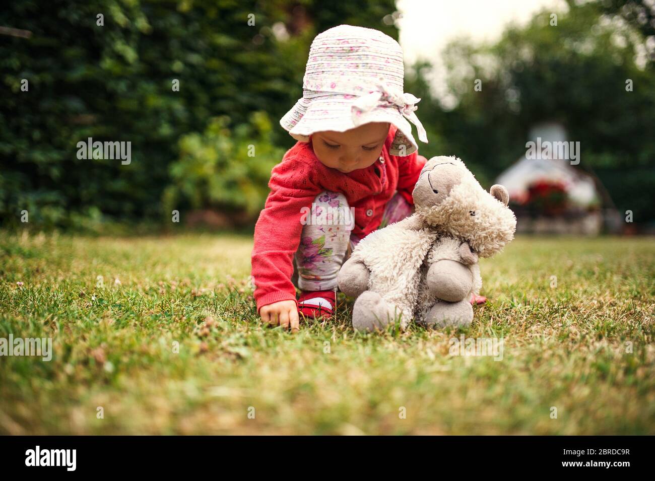 A front view of toddler girl outdoors in garden in summer. Stock Photo