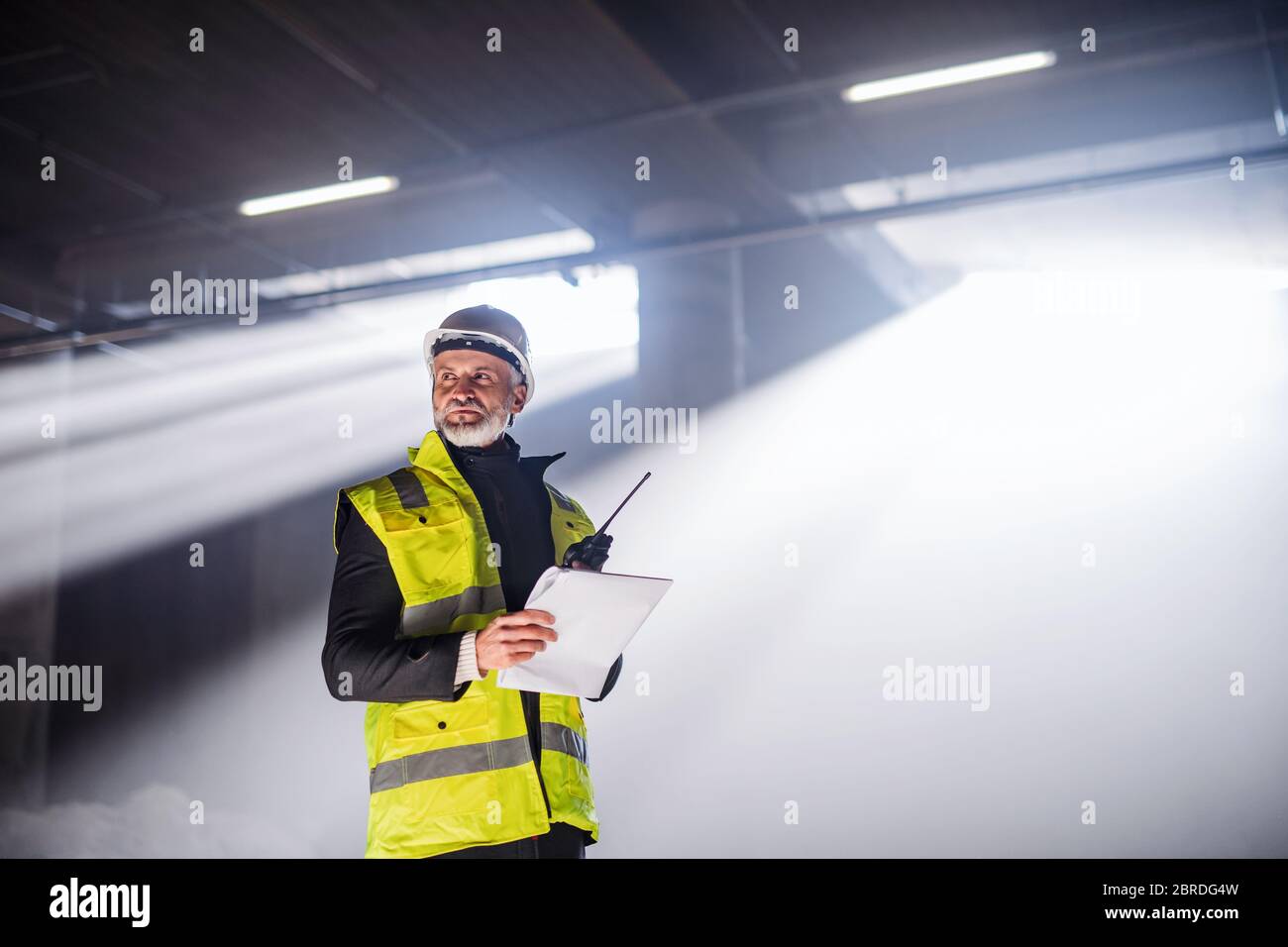 Man engineer using walkie talkie on construction site. Stock Photo