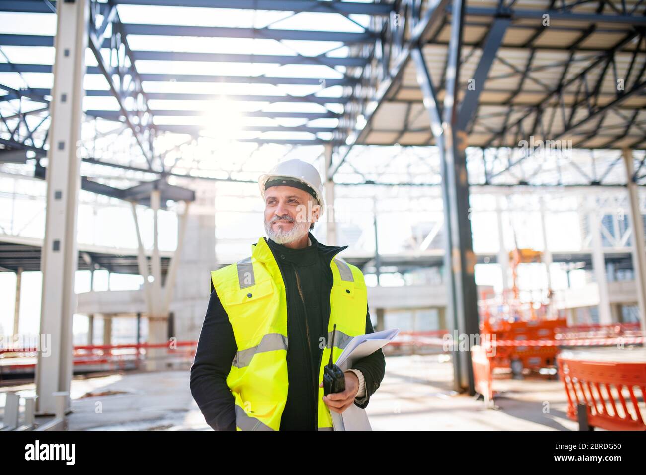Man engineer with walkie talkie standing on construction site. Stock Photo