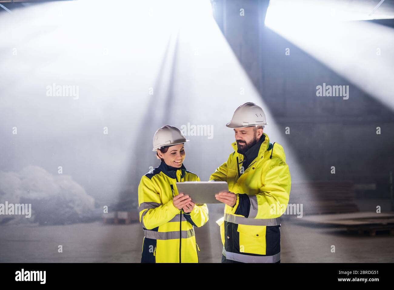 Engineers standing outdoors on construction site, holding tablet. Stock Photo