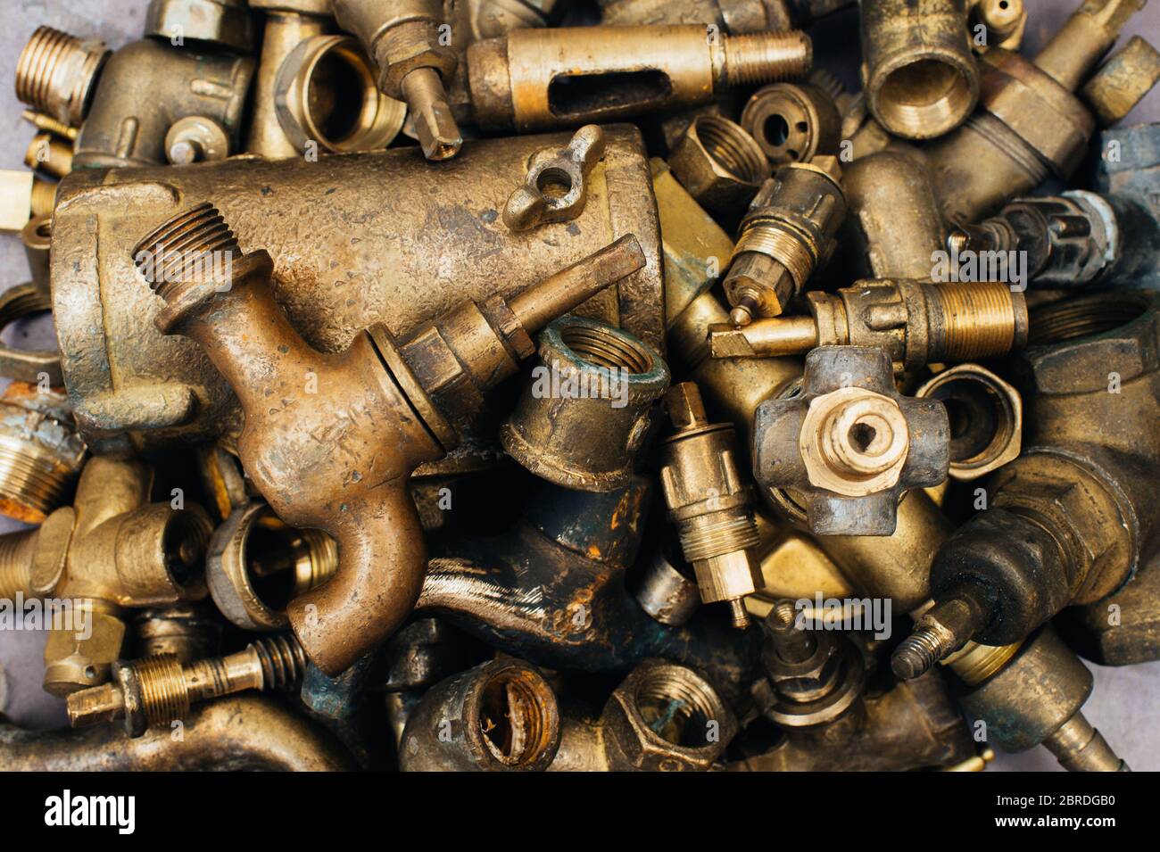 Brass scrap metal: taps, tees, plugs and various plumbing parts, spare  parts. Against the background of a copper sheet. Close-up Stock Photo -  Alamy