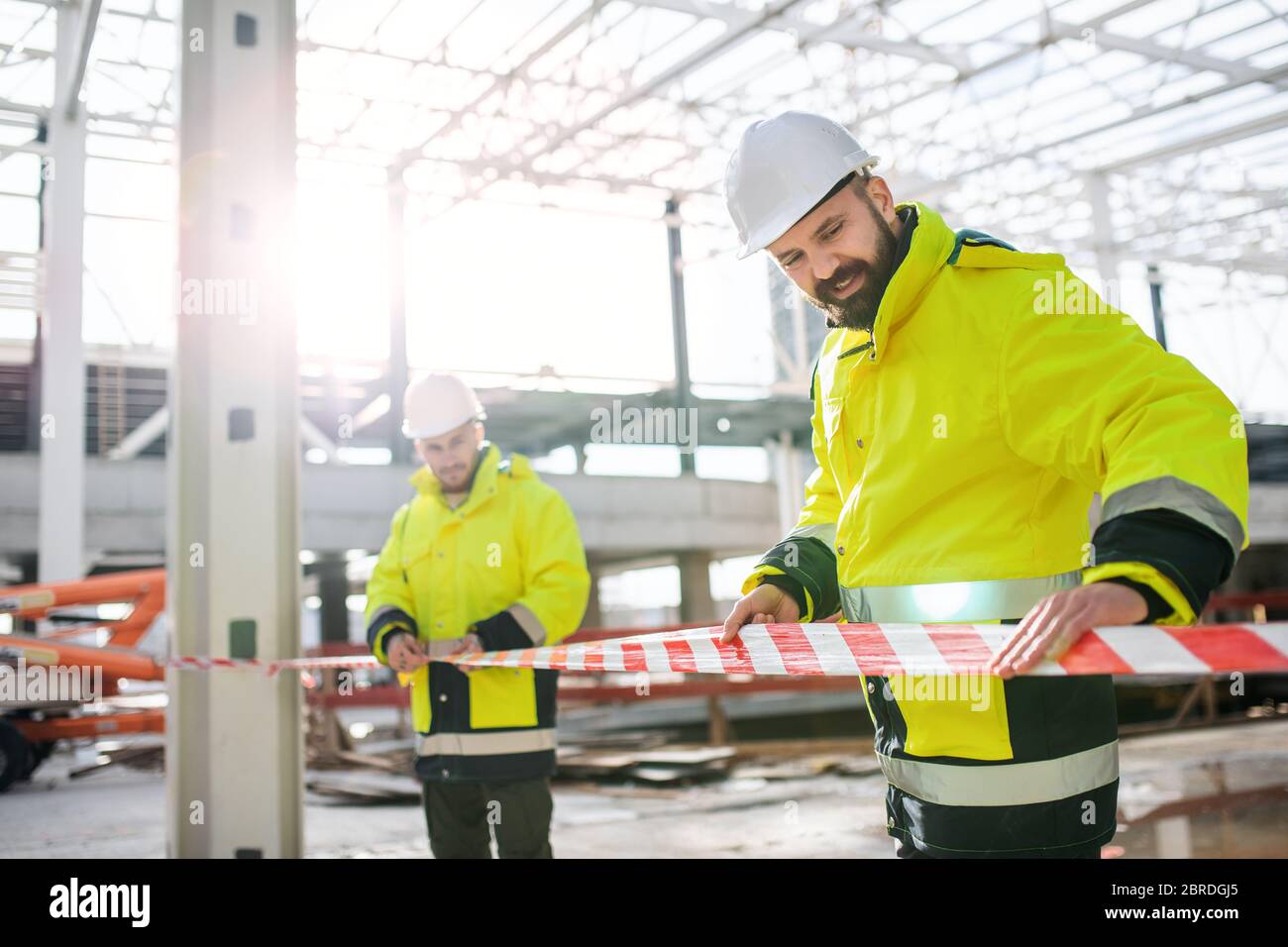 Men workers standing outdoors on construction site, working. Stock Photo