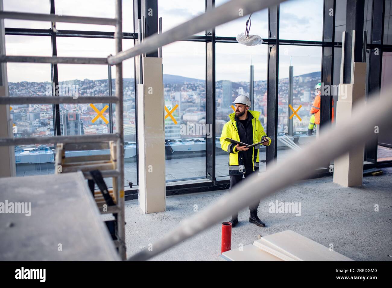 Man engineer standing on construction site, holding blueprints. Stock Photo