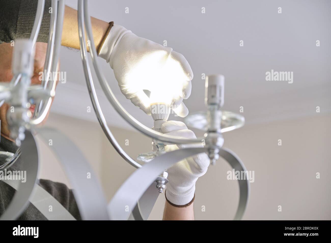 Installation ceiling lamp, hands of electrician fixing chandelier Stock