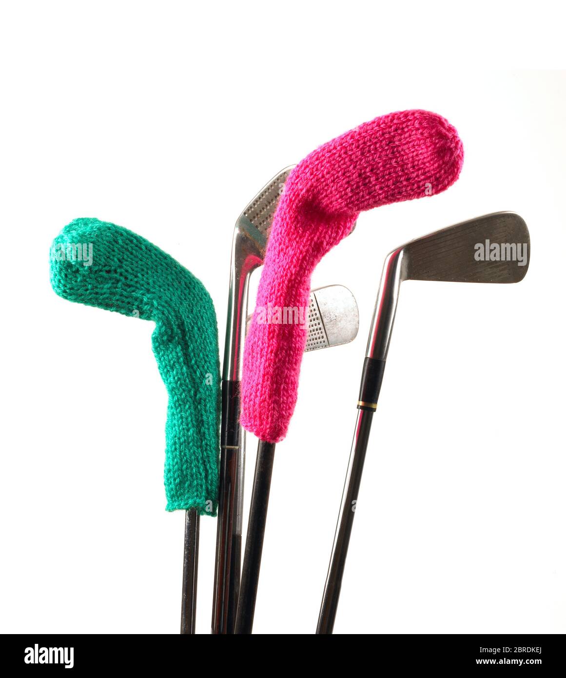 Golf Clubs with green and pink knitted woollen golf club covers on a white background Stock Photo
