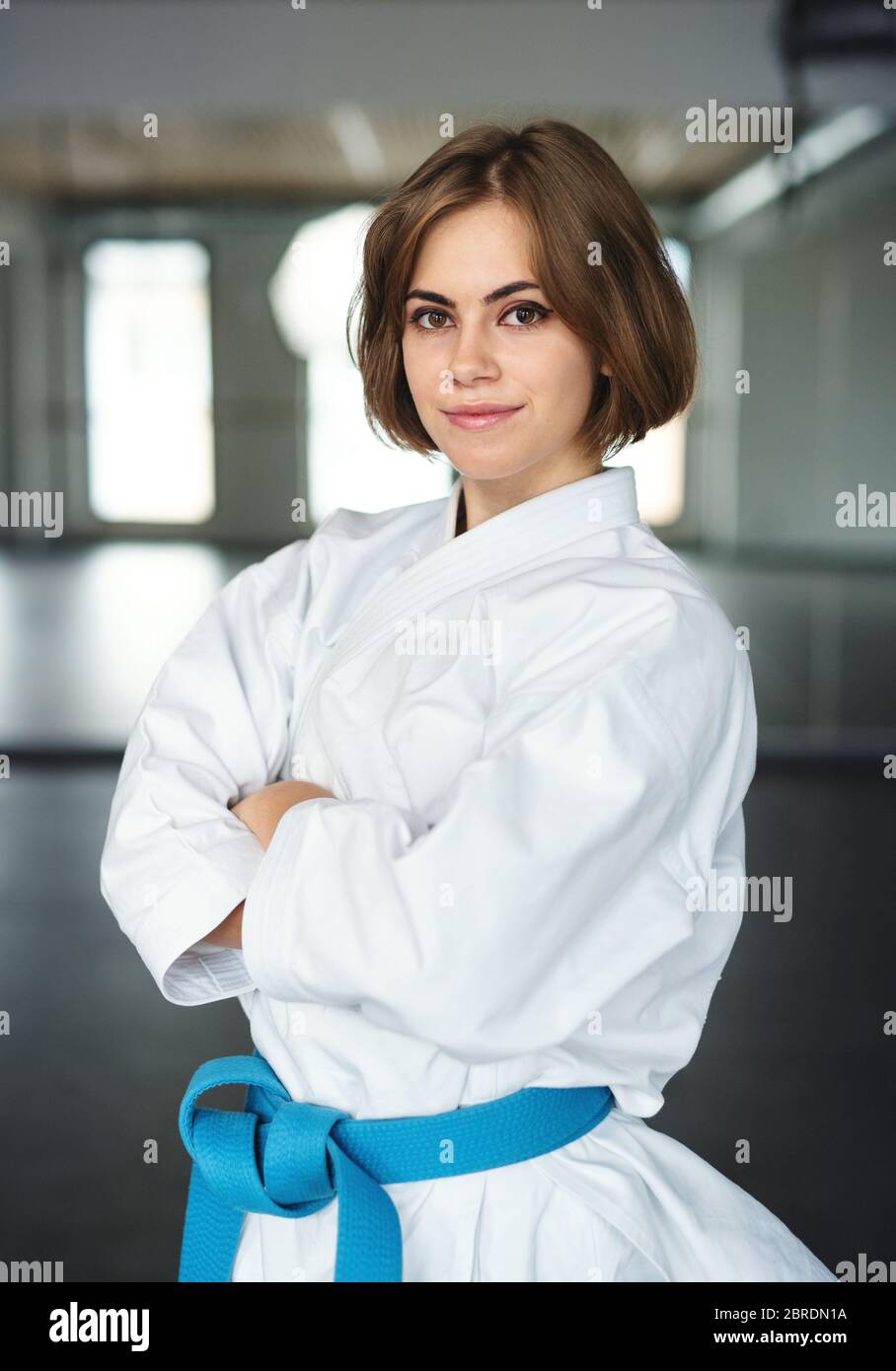 Young karate woman standing indoors in gym, looking at camera. Stock Photo