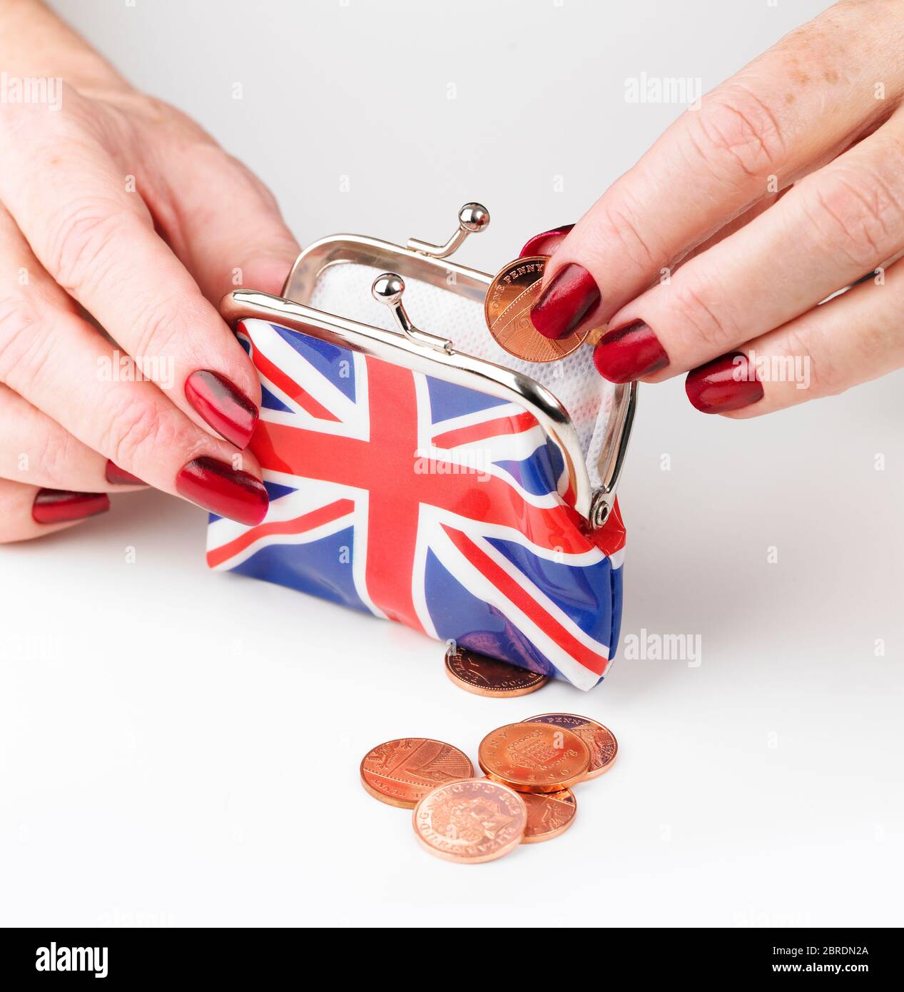 Hand putting pennies into Union Jack clasp purse Stock Photo