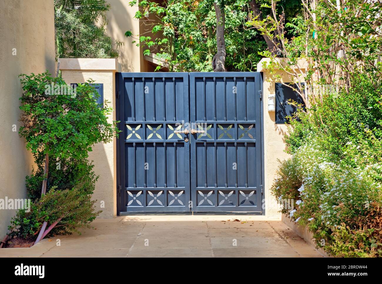 Entry black metal gates with gold handles in the garden Stock Photo
