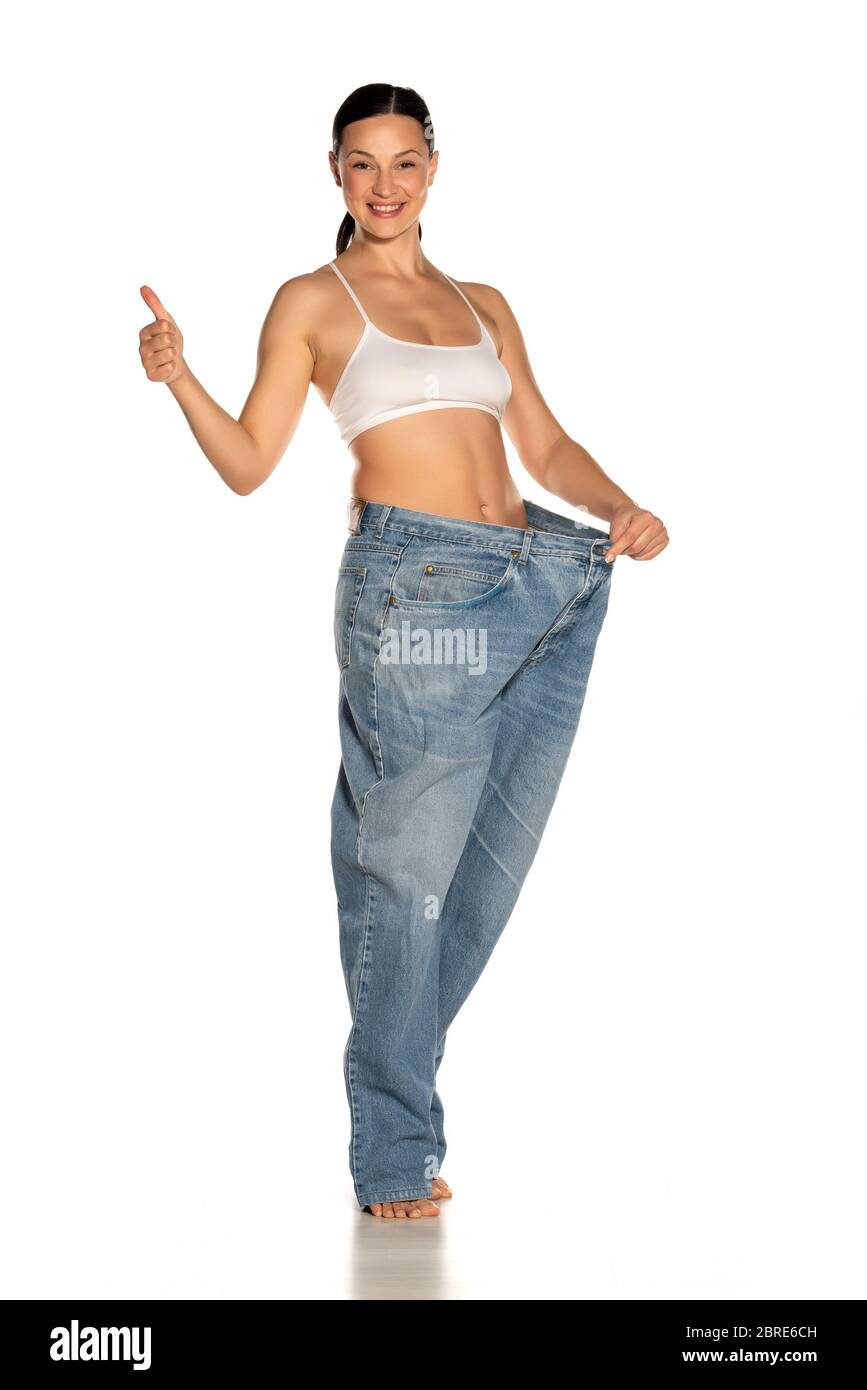 https://c8.alamy.com/comp/2BRE6CH/young-slim-woman-in-big-size-pants-showing-thumbs-up-on-white-background-2BRE6CH.jpg
