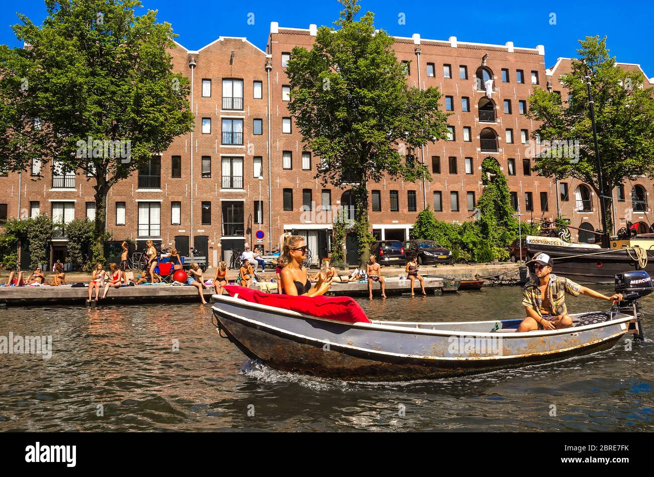 AMSTERDAM, HOLLAND – AUG. 31, 2019: Tourists and happy families relaxing and enjoying summer vacation on sunny days at Amstel river (city canal). Stock Photo