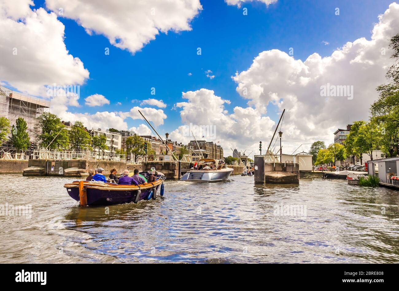 AMSTERDAM, HOLLAND – AUG. 31, 2019: Tourists and happy families relaxing and enjoying summer vacation on sunny days at Amstel river (city canal). Stock Photo